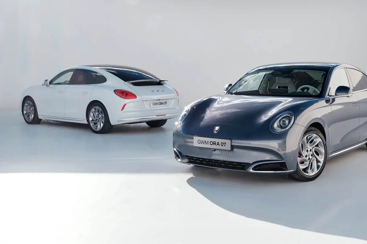 Zwei moderne Elektroautos vom Typ GWM ORA 07 stehen nebeneinander in einem hellen, minimalistischen Studio.