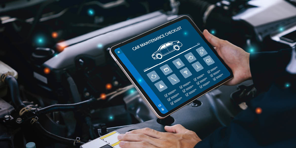 Ein Mechaniker überprüft mit einem Tablet eine digitale Wartungsliste vor einem offenen Auto-Motor.